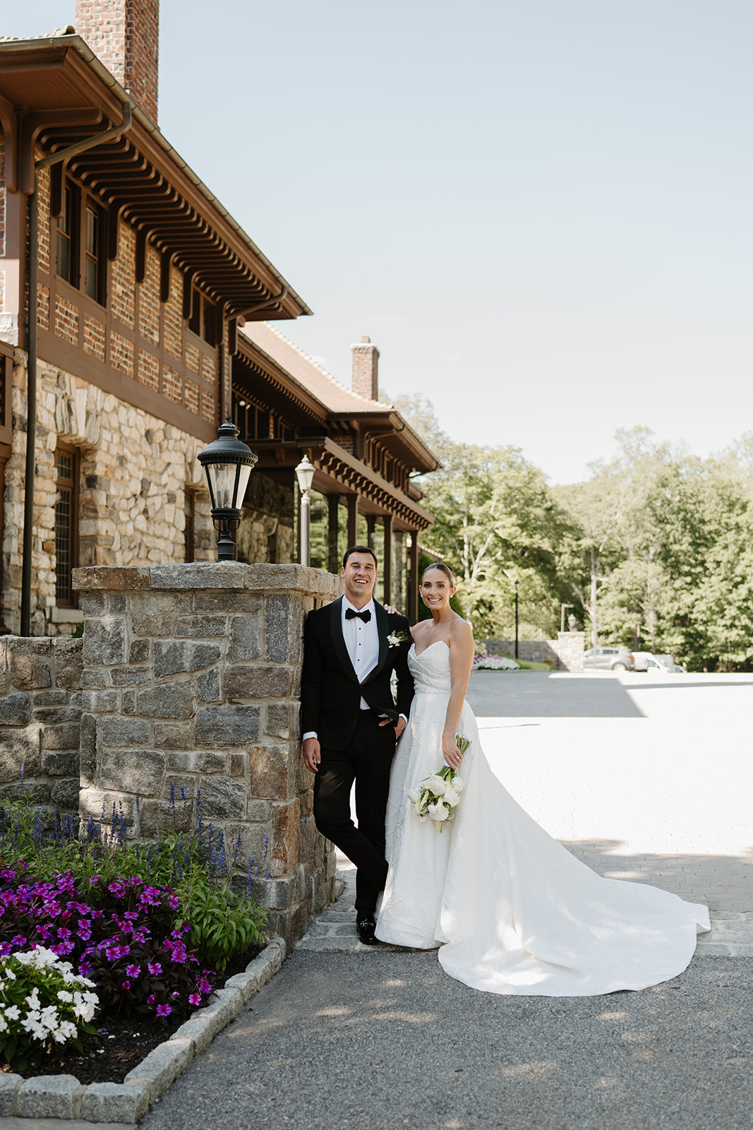 Bride and groom standing together outside the historic stone walls of the Le Chateau mansion.
